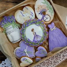 decorated cookies in a box with lace doily on the table next to flowers and vases