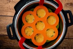 an overhead view of some food in a pot with red handles on a wooden table