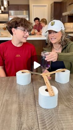 two people sitting at a table with toilet paper