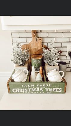 a wooden crate filled with potted plants on top of a counter next to a sign that says farm fresh christmas trees