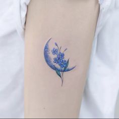 a woman's arm with a blue flower tattoo on the left side of her arm