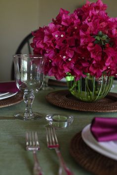 pink flowers in a glass vase on a table set with silverware and utensils