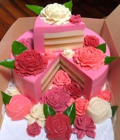 a pink cake with flowers on it in a box