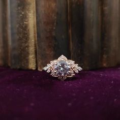 an engagement ring sitting on top of a purple velvet