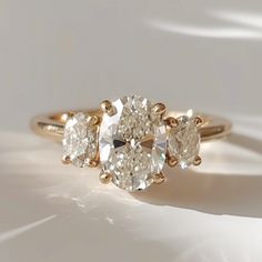 three stone diamond ring on white surface with shadows in the back drop down from above