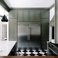 a kitchen with green cabinets and black and white checkered flooring on the tile