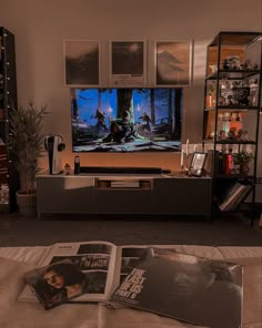 an entertainment center in a living room with posters on the wall and magazines laying on the floor