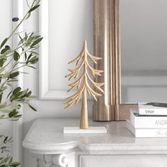 a white table topped with books and a gold christmas tree decoration on top of it