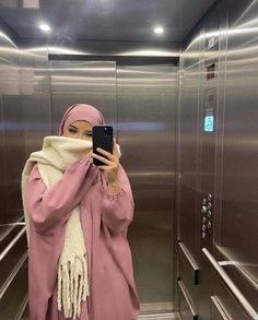 a woman in a pink hijab taking a selfie with her cell phone