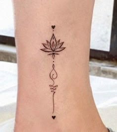 a small tattoo on the ankle with a lotus flower and heart shaped drops in black ink