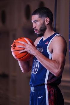 a man holding a basketball in his right hand and looking at the ball he is holding