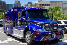 a large blue truck is driving down the street with other cars in the back ground