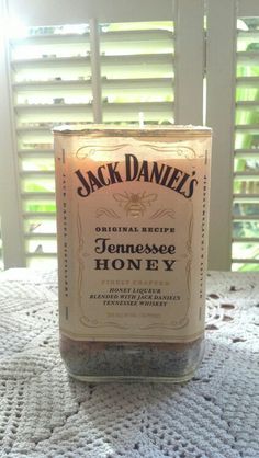 a jar of jack daniels honey sitting on top of a table next to a window