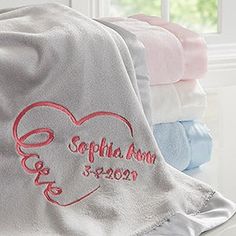 the personalized blanket is next to several folded towels on a window sill in front of a window