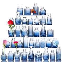 many blue vases and flowers are arranged on a shelf with one red rose in the middle