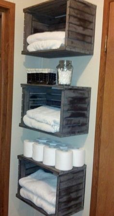 three wooden crates are stacked on top of each other to hold toilet paper and towels