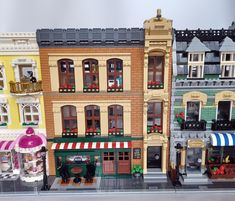 there are many lego buildings on display in front of the storefronts and windows