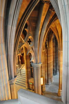 the interior of an old cathedral with stone columns and arches, looking down at stairs