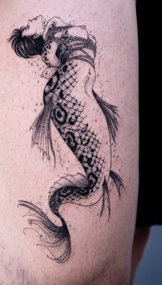 a woman with a fish tattoo on her thigh is shown in black and grey ink