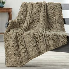 a knitted blanket sitting on top of a wooden bench