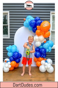 Child holding a Nerf blaster in front of a balloon arch with blue, orange, and white balloons. Party Stations, 7 Birthday, 4 Birthday, Themed Decorations