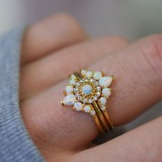 a close up of a person's hand wearing a ring with opal stones