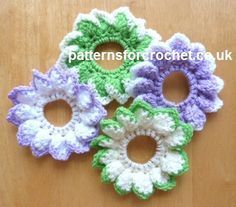 four crocheted flowers on a wooden surface