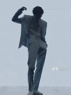 a man in a suit and tie is standing on the ground with his hands behind his head