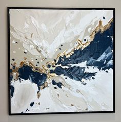 an abstract painting with gold and blue colors on the wall in a white walled room