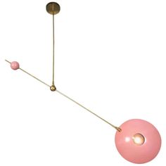 a pink ball hanging from a long brass rod