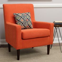 an orange chair sitting in front of a painting