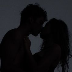 two people are kissing in the dark with their heads touching each other's shoulders