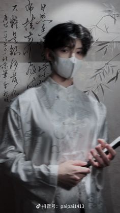 a woman wearing a face mask and holding a book in front of a wall with writing on it