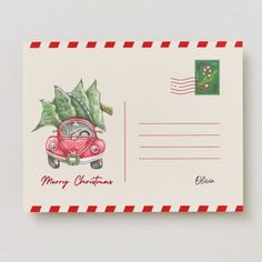 a christmas postcard with a red car and holly on the top, in front of a green envelope