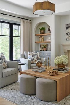 a living room filled with furniture and a fire place under a chandelier in front of a window