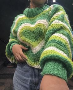 a woman wearing a green and white knitted sweater with a heart on the chest