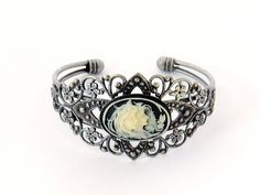 Two Sisters Cameo Bracelet/Victorian Cameo Bracelet/Cameo/Victorian Cameo Jewelry/Sisters Cameo/Silver Cameo Cuff Bracelet/Wedding Jewelry Victorian Cameo Cuff Bracelet featuring two sisters 25 x 18 mm cameo on a black background set in an antiqued pewter filigree cuff bracelet. Also available in blue. Beautifully detailed antiqued pewter finished brass cuff adjusts to comfortably fit a wrist between 5.75 and 7.75 inches. This is a popular gift for sisters and best friends. Brides - Please convo Victorian Bangle As Gift, Victorian Cuff Bracelet For Wedding, Victorian Antique Silver Bracelets For Wedding, Antique Adjustable Cuff Bracelet For Wedding, Silver Cameo Bracelet For Gifts, Elegant Silver Bracelet With Cameo, Vintage Silver Cameo Bracelet, Vintage Antique Silver Cuff Bracelet, Ornate Antique Silver Cuff Bracelet For Weddings