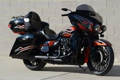 a black and orange motorcycle parked in front of a brick wall with a helmet on it's back end