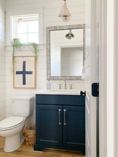 a white toilet sitting next to a sink in a bathroom under a framed cross on the wall