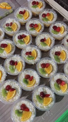 there are many desserts in plastic cups on the table with fruit and kiwi slices