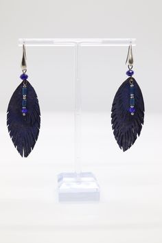 Blue feather earrings are delicate accessories crafted with vibrant blue feathers, elegantly dangling from a gold hook, adding a touch of nature-inspired beauty to any outfit. Their graceful design complements both casual and formal styles, making them a versatile and eye-catching addition to any jewelry collection. Adjustable Blue Feather Earrings, Elegant Blue Feather Earrings, Blue Feather Earrings As Gift, Blue Feather Earrings Gift, Blue Feather Earrings For Gift, Blue Feather Dangle Earrings, Elegant Adjustable Feather Earrings, Elegant Feather Earrings, Blue Feathers