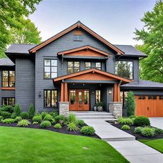 a large gray house with wood trimmings and two garage doors on the front