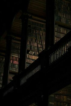 an image of a clock that is on the side of a book shelf at night