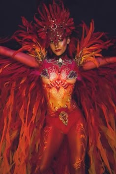 a woman dressed in red and gold with feathers on her head, holding two hands behind her back