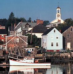 a boat is docked in the water next to some buildings and a church steeple