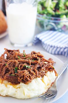 a white plate topped with mashed potatoes and beef