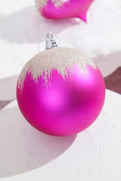 two pink ornaments sitting on top of a white table