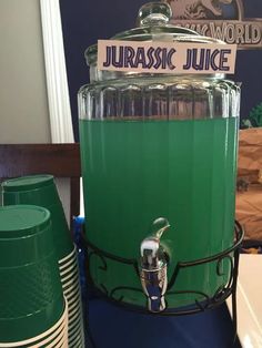 a green juicing machine sitting on top of a counter next to stacks of plates