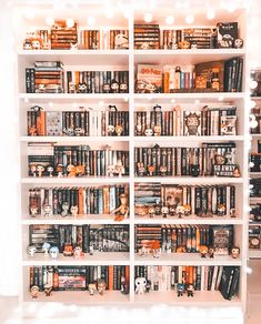 a bookshelf filled with lots of books on top of white shelves covered in lights