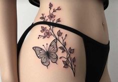 a woman's stomach with a butterfly tattoo on the side of her body and flowers